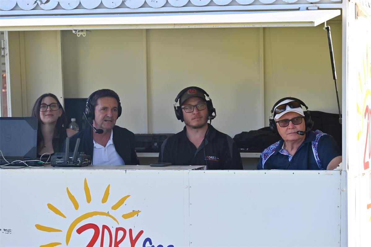 Four people sitting in a booth with headsets on 
